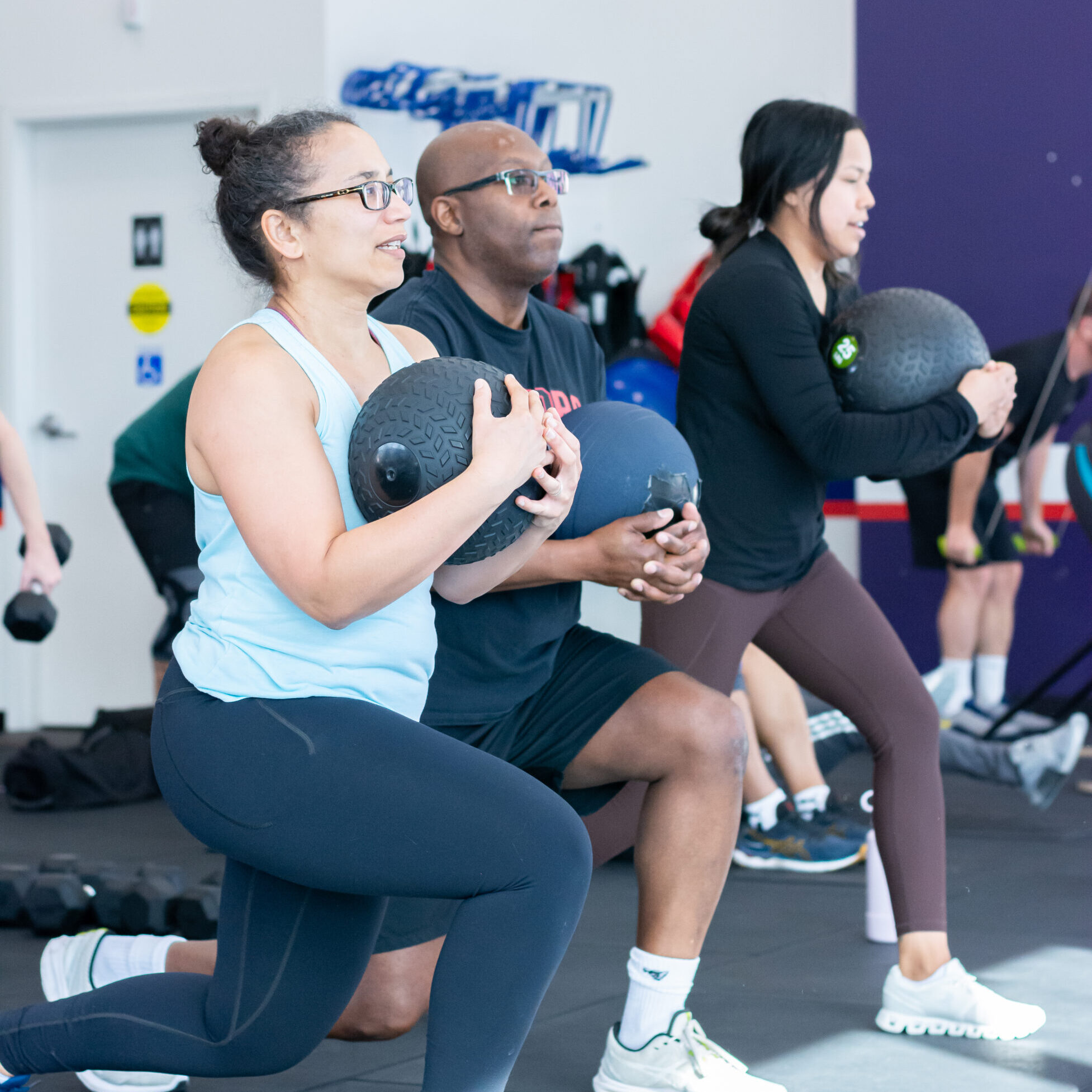 A man and woman squating with a weighted ball at F45 Sunnylea